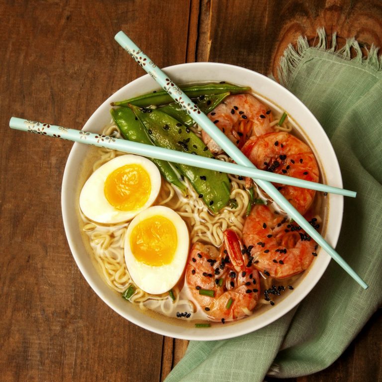 A bowl of Japanese ramen with egg, shrimp and snow peas