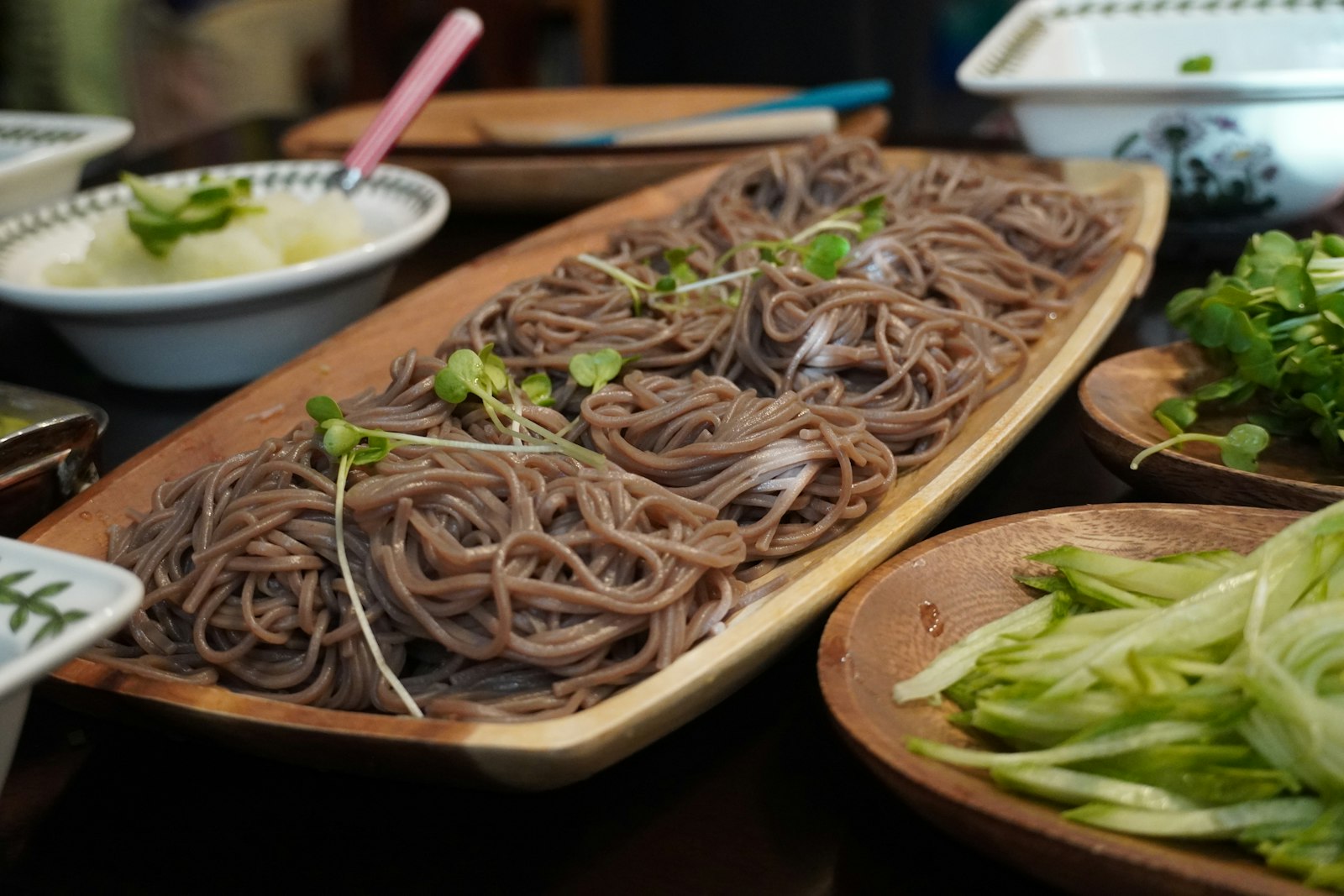 Cold soba noodles served on a wooden tray with garnishes