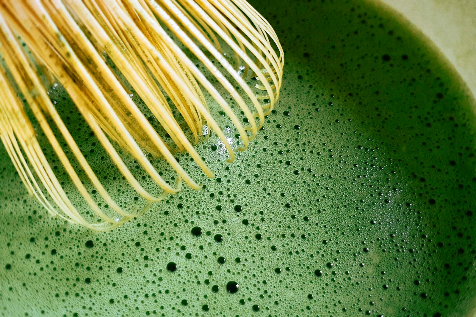 A bamboo whisk (chasen) frothing matcha in a bowl (chawan)