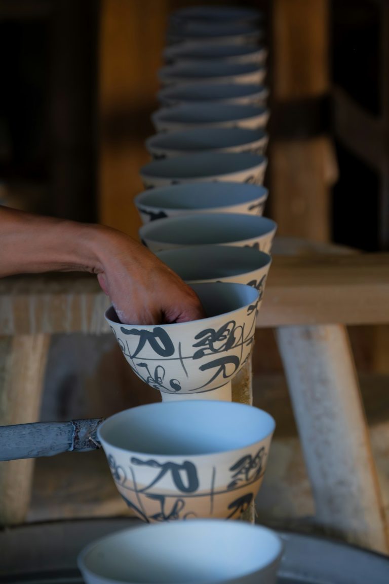A hand reaching for a stack of Japanese ceramic bowls