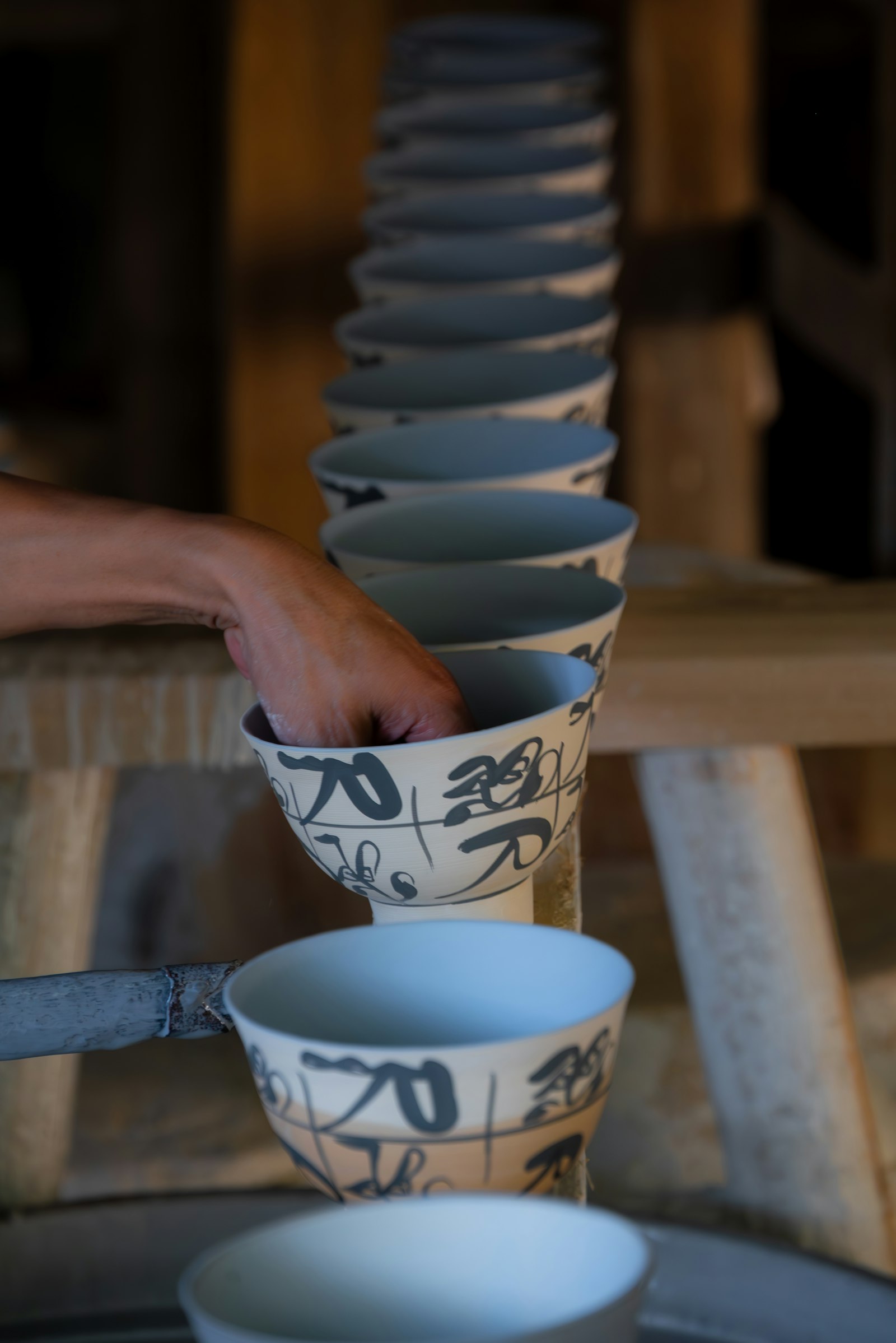 A hand reaching for a stack of Japanese ceramic bowls