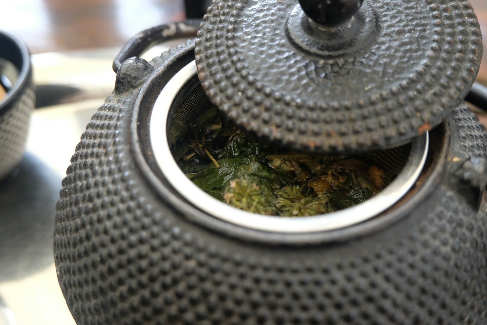 A Japanese cast iron teapot with a raised arare dot texture and top handle