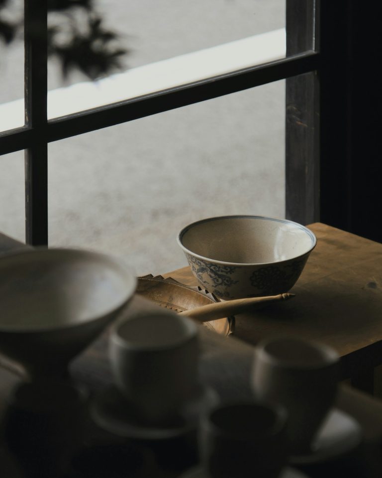 White and blue Japanese ceramic bowls on a wooden table by a window