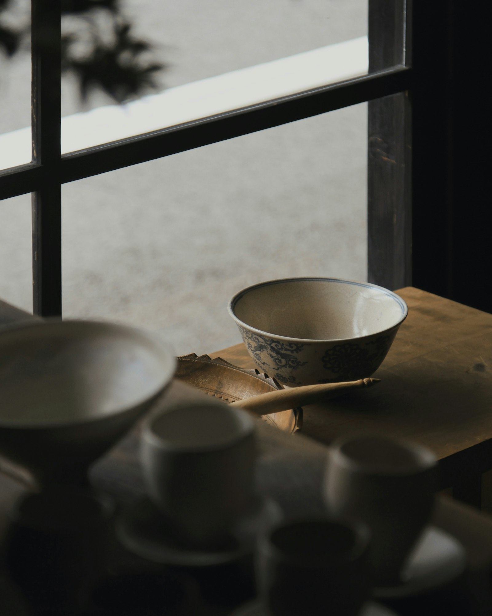 White and blue Japanese ceramic bowls on a wooden table by a window